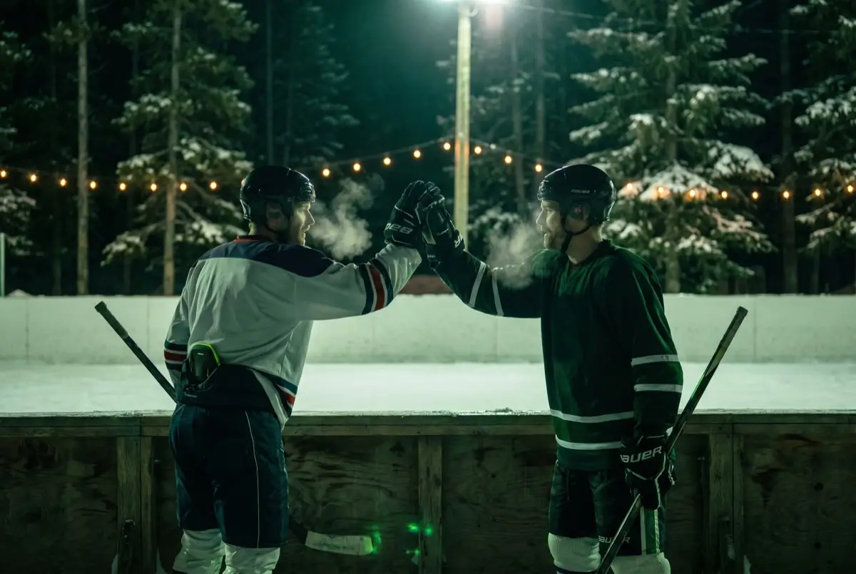 Two adult players in gear knocking gloves at the boards